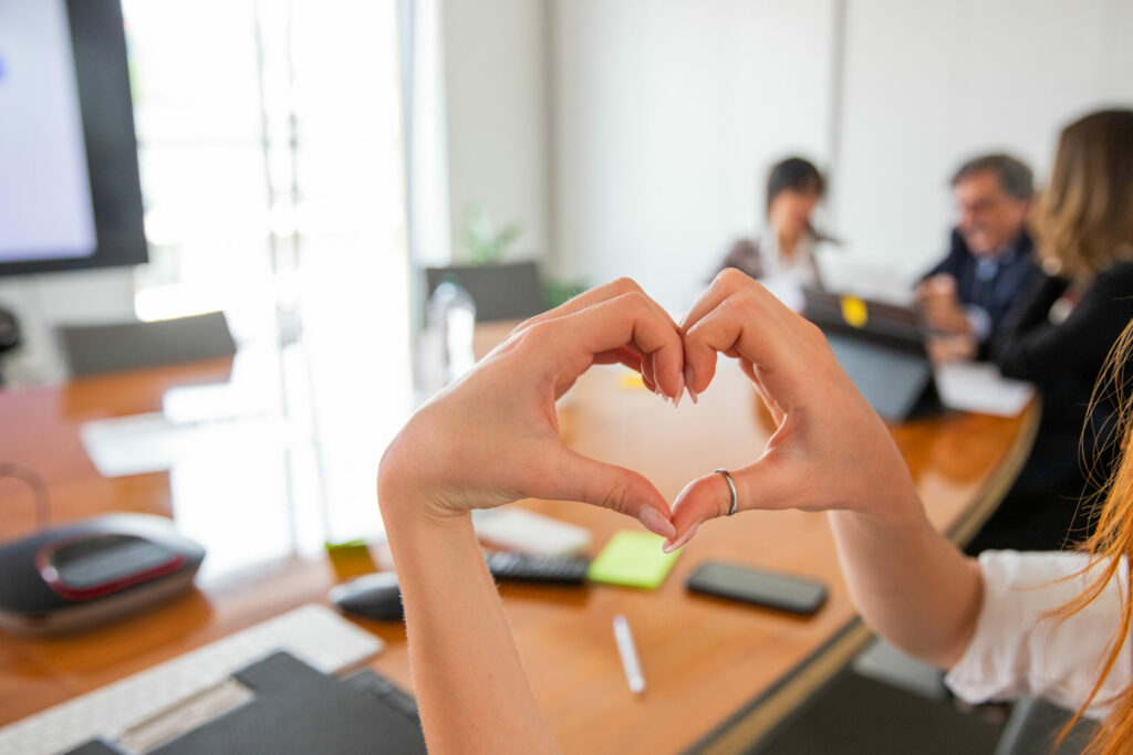 La femme fait un cœur avec ses mains dans le bureau, l’amour pour le concept de lieu de travail