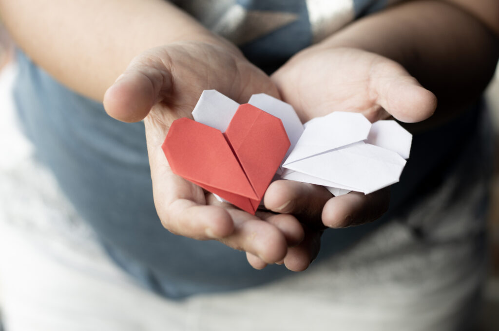 Mains qui offrent des coeurs en origami